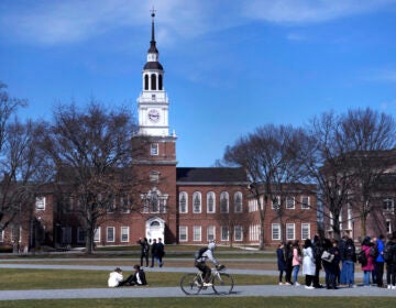 FILE - A bicyclist passes a college tour group outside the Baker Library at Dartmouth College, April 7, 2023, in Hanover, N.H. (AP Photo/Charles Krupa, File)