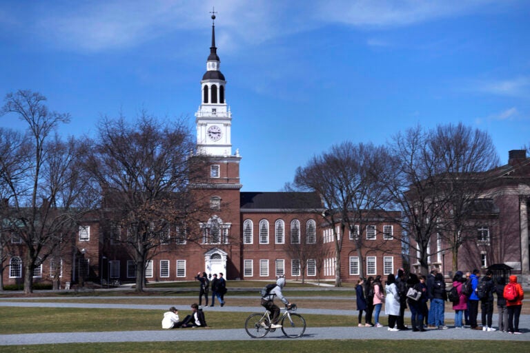 FILE - A bicyclist passes a college tour group outside the Baker Library at Dartmouth College, April 7, 2023, in Hanover, N.H. (AP Photo/Charles Krupa, File)