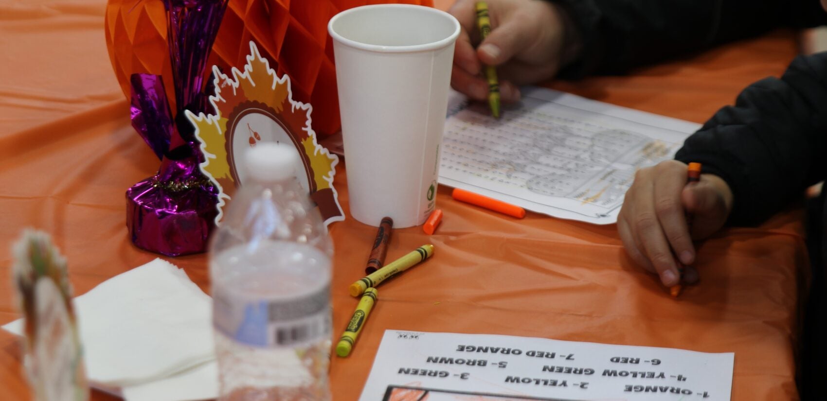 kids play with pages for coloring and a word puzzle on a table