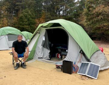 Danny Rickapauth sits by a tent