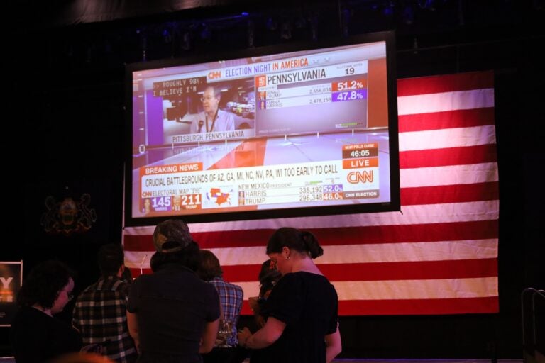 a projection screen shows CNN at the watch party