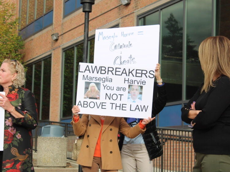 Republicans hold signs condemning commissioners