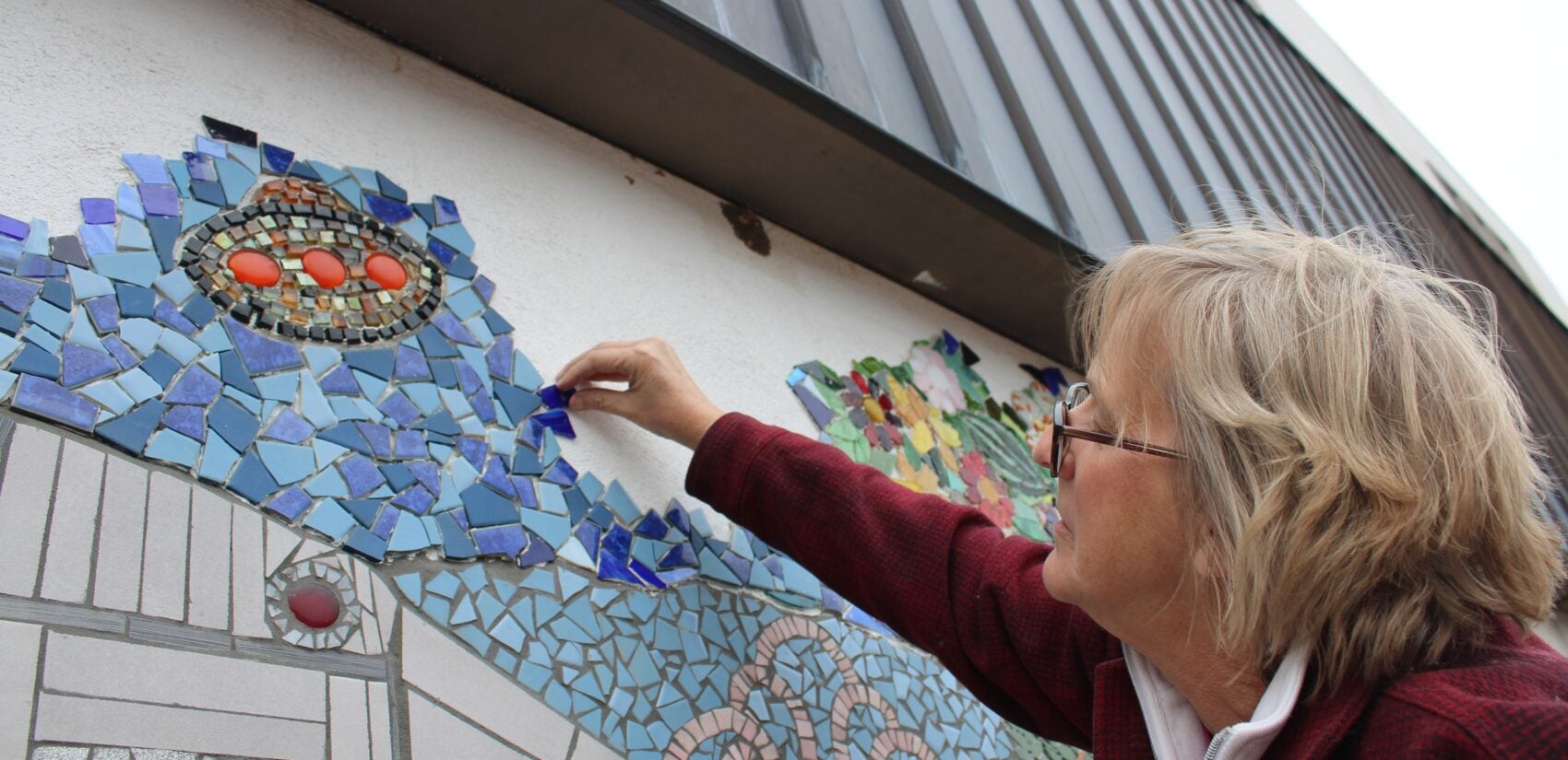 Roxanne Slemmer adds a tile to the mural