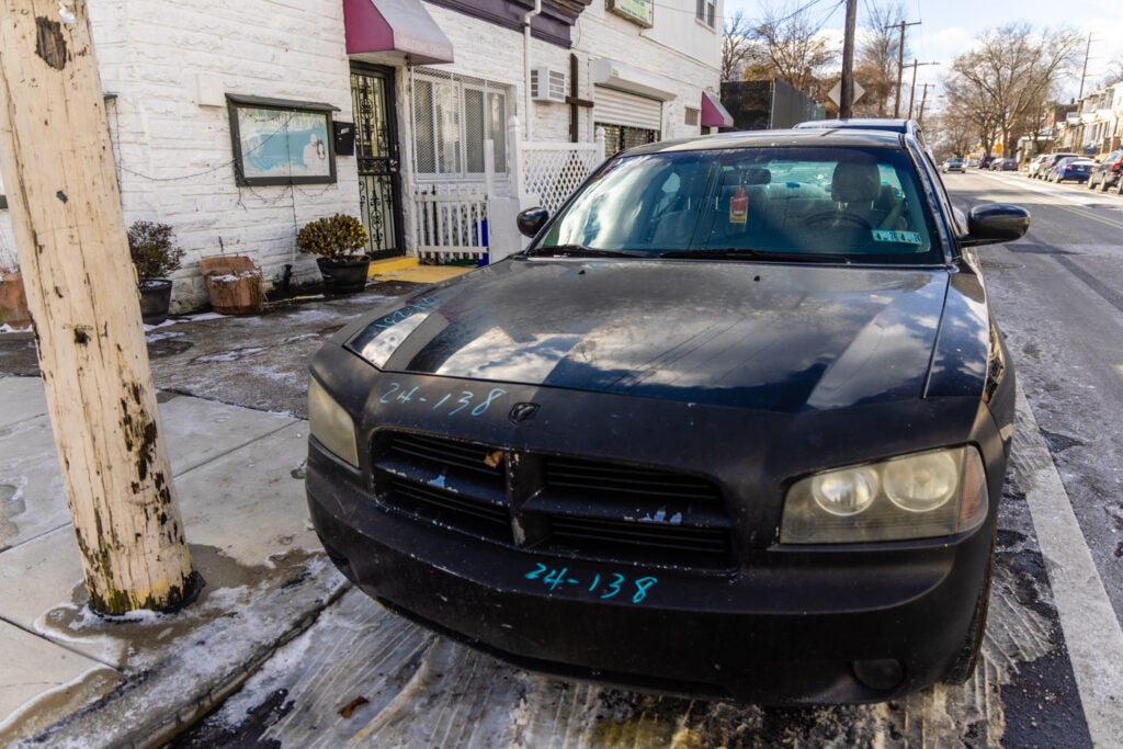 An abandoned car parked in the street on a residential block