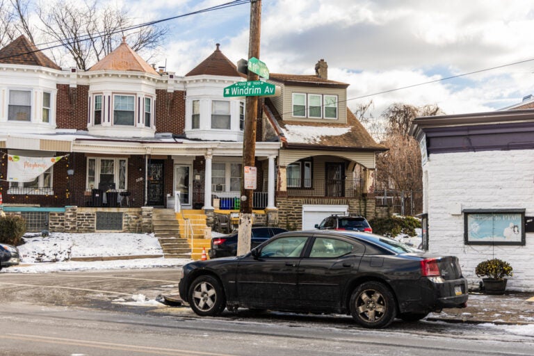 An abandoned car parked in the street on a residential block