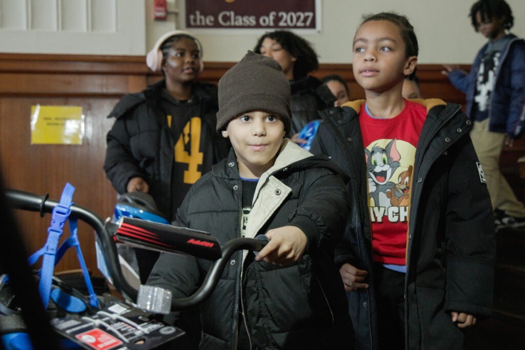 Allah Dalili holds a bike with other students