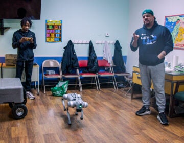 Aaron Campbell speaks next to Sybir Brown and a robotic dog