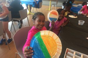 2 young girls holding up artwork they made at school