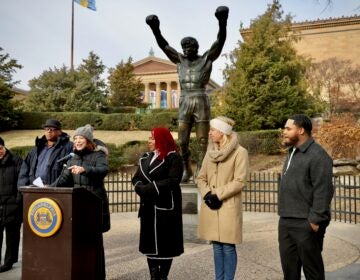 Several people standing behind a podium placed in front of the Rocky statue