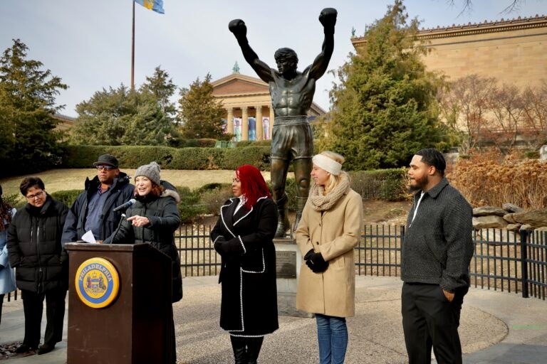 Several people standing behind a podium placed in front of the Rocky statue