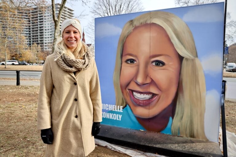 Michelle Konkoly posing next to a large portrait of her