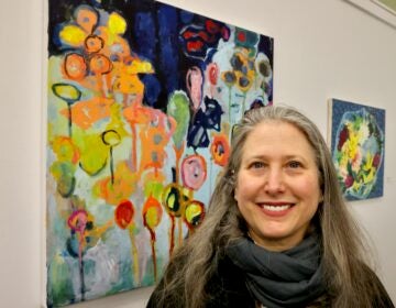 Erin Elman smiles next to her painting