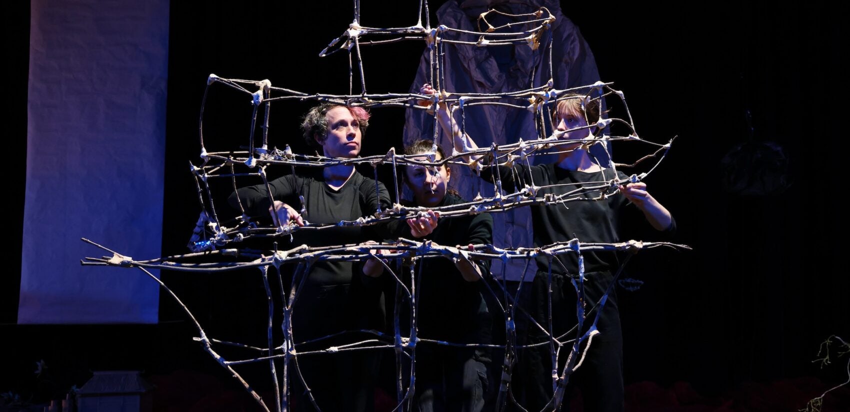 Three dancers assemble an ark on stage