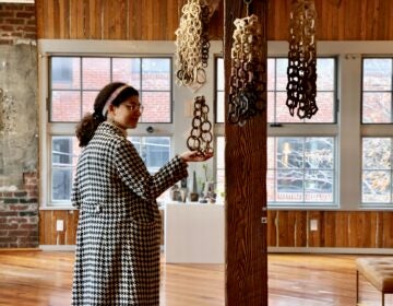 Hazami Sayd's links are made to be touched gently. They make a chiming sound when handled. Pictured is the artist's daughter-in-law, Christina Ingraldi. (Emma Lee/WHYY)