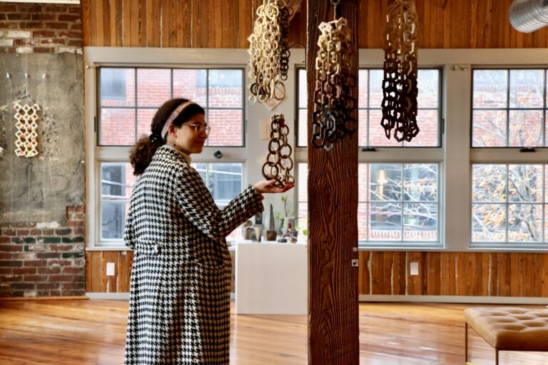 Hazami Sayd's links are made to be touched gently. They make a chiming sound when handled. Pictured is the artist's daughter-in-law, Christina Ingraldi. (Emma Lee/WHYY)