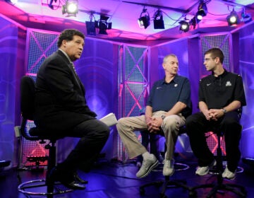 FILE - Greg Gumbel, left, watches as Connecticut head coach Jim Calhoun talks to Butler head coach Brad Stevens, right, prior to taping a television interview for the men's NCAA Final Four college basketball championship game Sunday, April 3, 2011, in Houston. (AP Photo/Eric Gay, File)