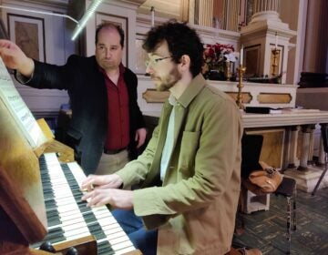 John Walhausen plays the organ in the church while Benjamin Boyle turns the pages on a music book