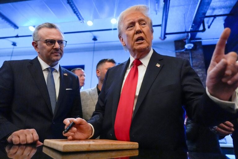 Donald Trump signs autographs as Massad Boulos listens