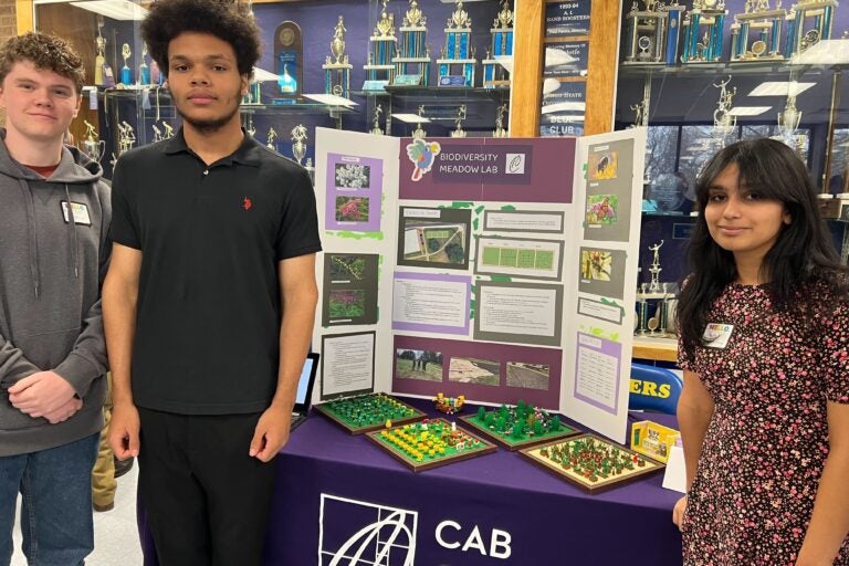 3 students posing for a photo with their project