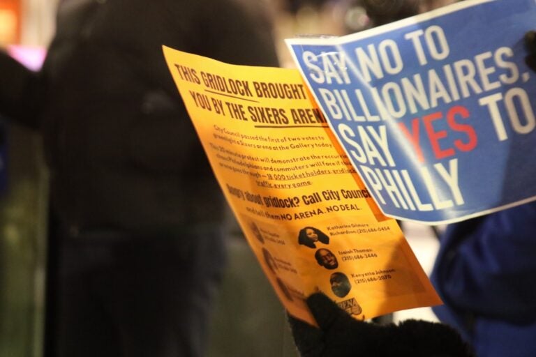 Protesters holding flyers explaining their protest, and signs they are holding up