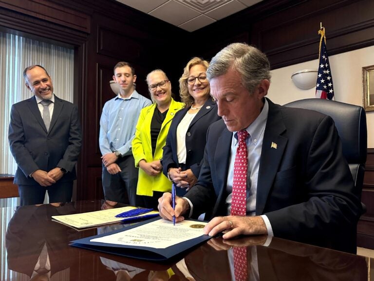 John Carney signing legislation as four others look on