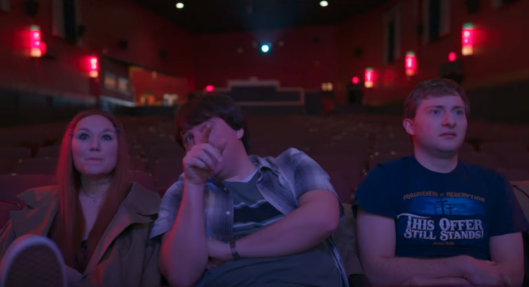 Three people sit in a theater