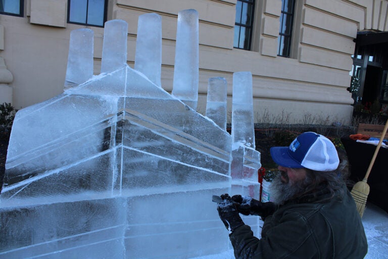 Roger Wing carves an ice sculpture of The Battery in a live ice sculpting demonstrations at the 6th annual Fishtown Freeze event on Dec. 14, 2024. (Emily Neil/WHYY)