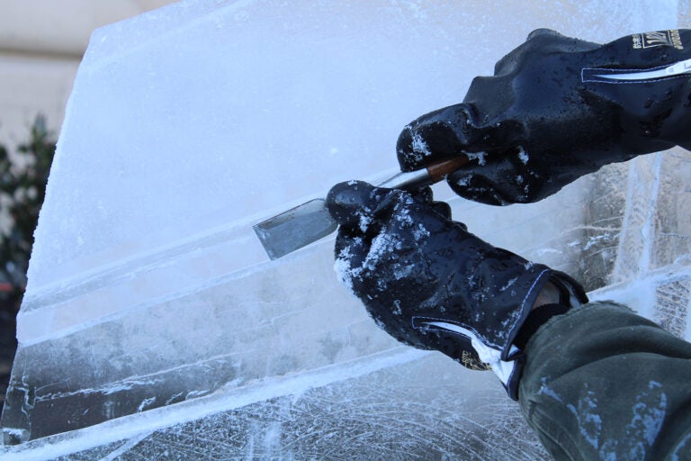 Roger Wing carves an ice sculpture of The Battery in a live ice sculpting demonstrations at the 6th annual Fishtown Freeze event on Dec. 14, 2024. (Emily Neil/WHYY)