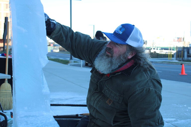 Roger Wing carves an ice sculpture of The Battery in a live ice sculpting demonstrations at the 6th annual Fishtown Freeze event on Dec. 14, 2024. (Emily Neil/WHYY)