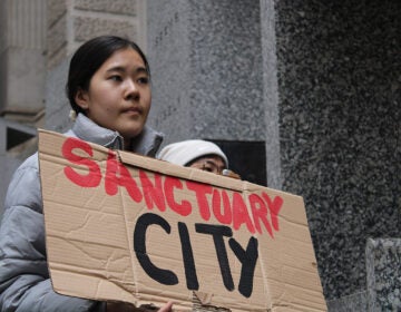 Dozens rallied at City Hall on Dec. 10, 2024, calling on Philadelphia elected officials to reaffirm sanctuary city protections for undocumented residents. (Emily Neil/WHYY)