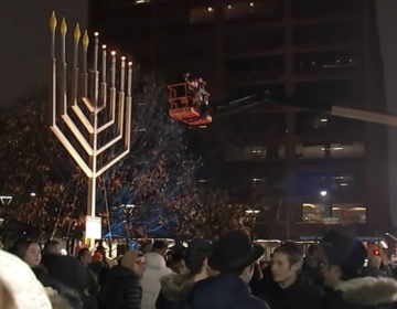 A 32-foot menorah being lit in front of a crowd