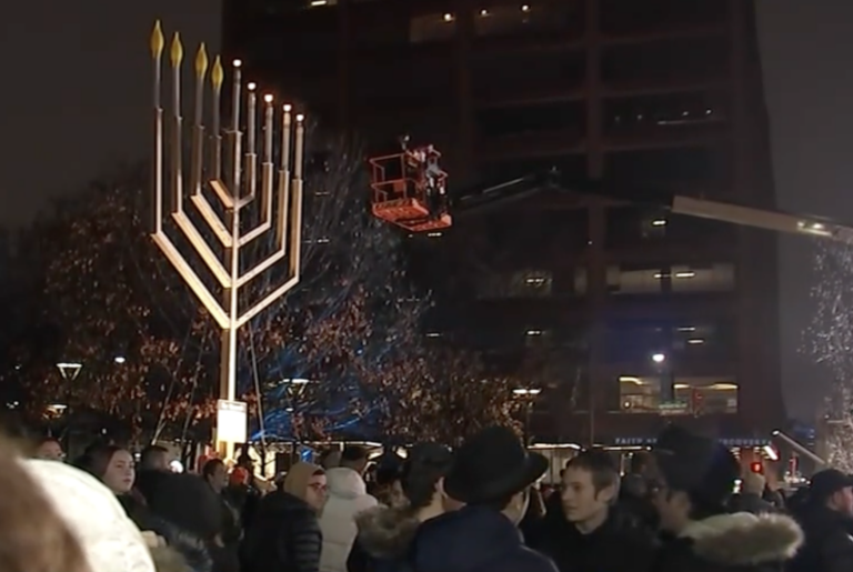 A 32-foot menorah being lit in front of a crowd