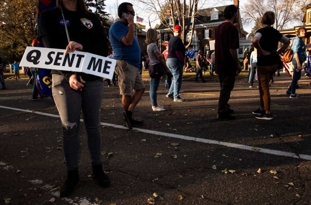 Woman holds a sign referencing the QAnon conspiracy