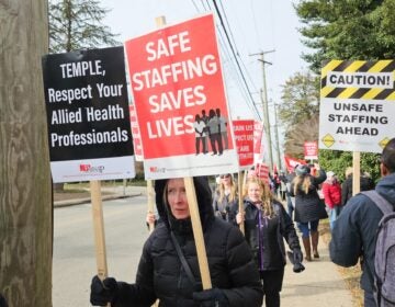 people marching on a picket line holding up signs