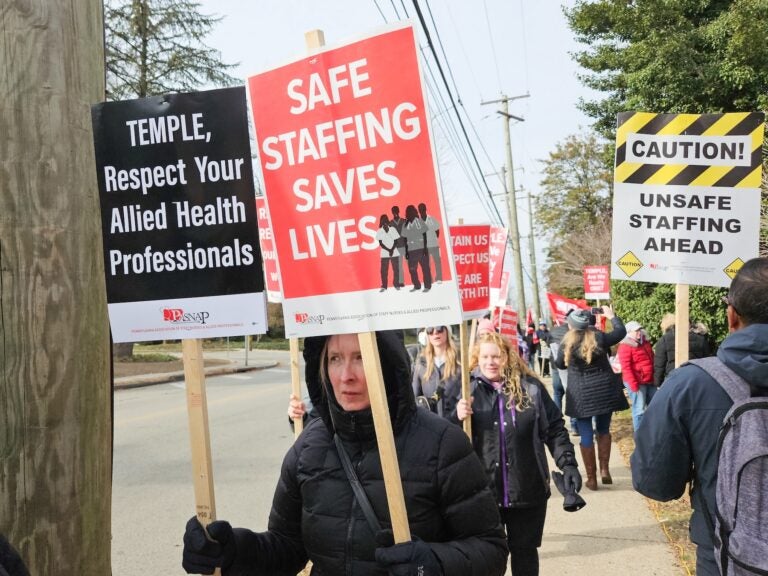 people marching on a picket line holding up signs