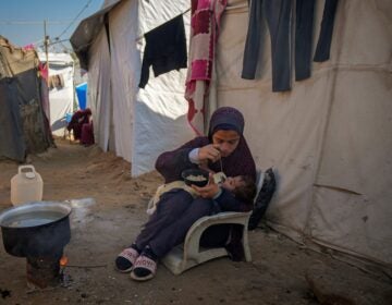 A 16-year-old feeds a baby at a camp for displaced Palestinians