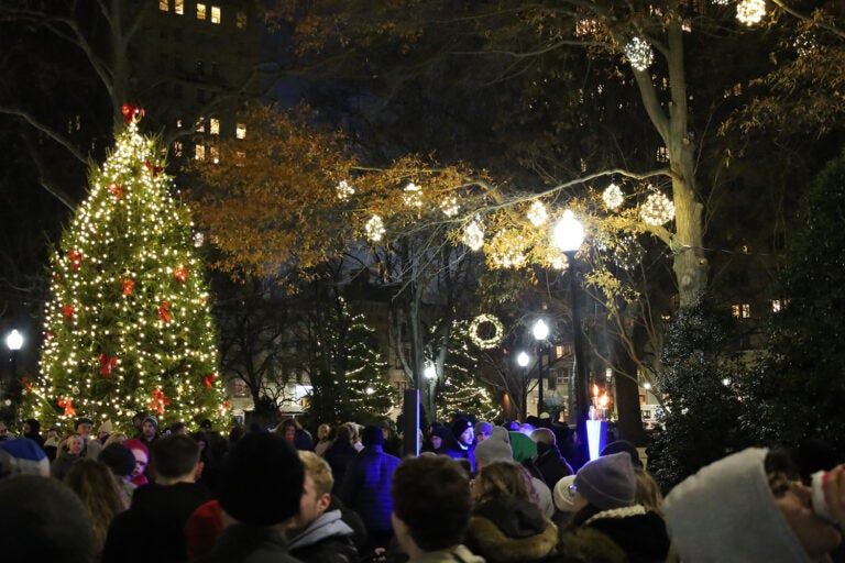 People stand near a lit Christmas tree in Rittenhouse Square in Philadelphia