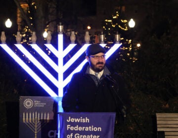 A male rabbi speaks in front of a menorah in Philadelphia