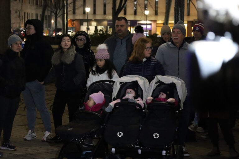 A woman pushes three children in a carriage among a group of people in Philadelphia