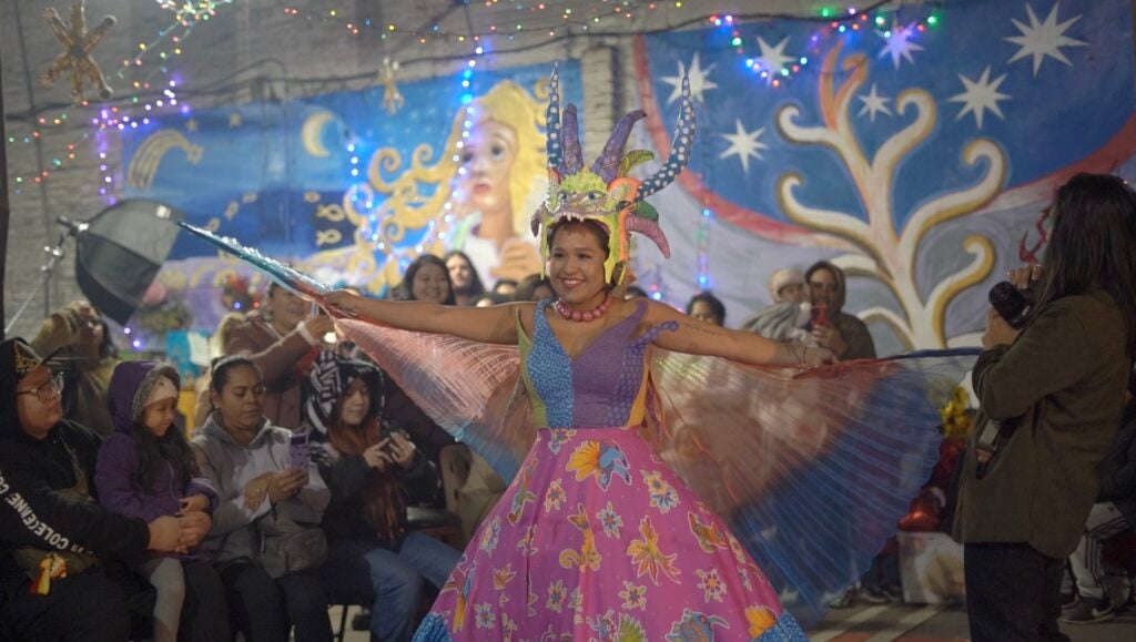 A woman in colorful dress dances in front of a crowd