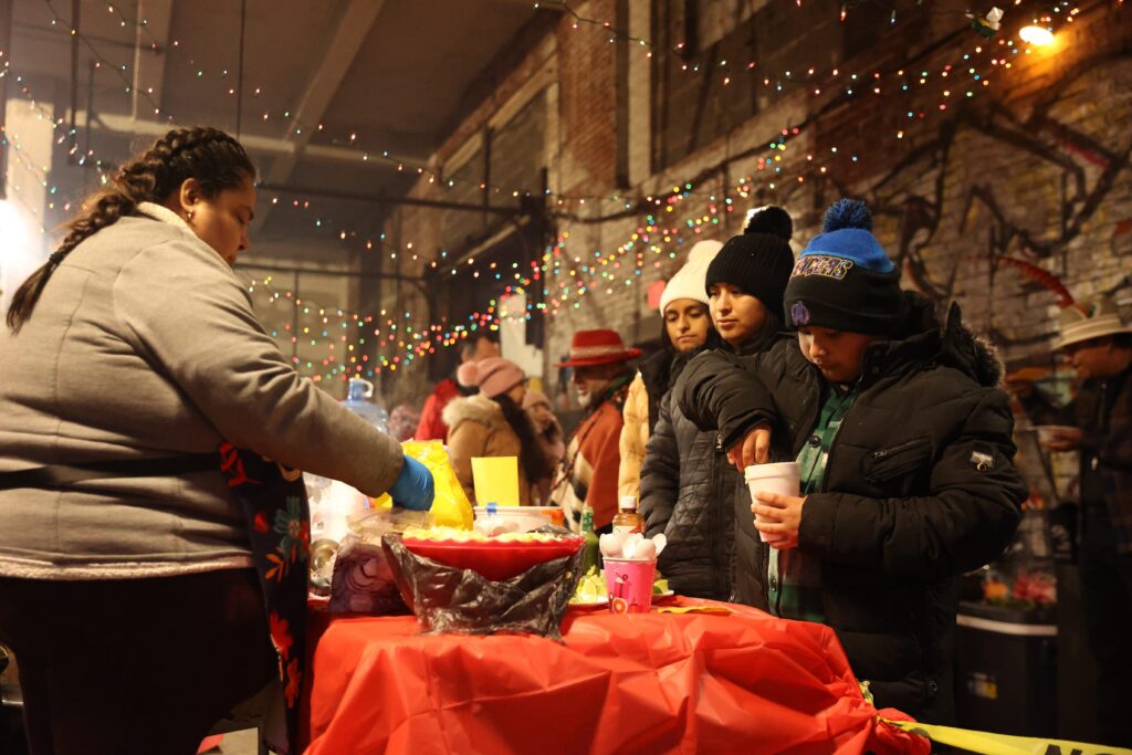 A woman shares pozole with the community