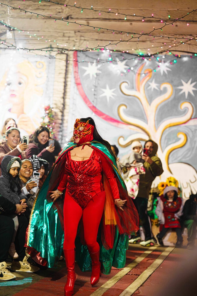 A woman in a red costume walks down a runway