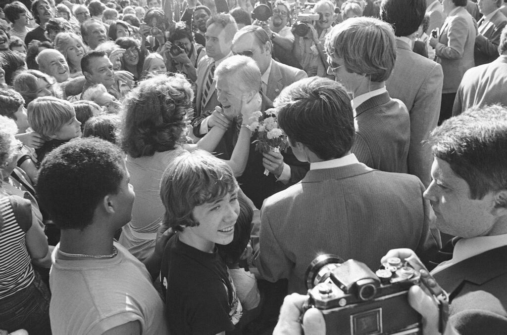 A Secret Service Agent helps U.S. President Jimmy Carter pull away from an unidentified woman who kissed him while he visited a family in suburban Lansdowne, Pennsylvania, Thursday, Oct. 2, 1980. Carter was spending part of Thursday in the Philadelphia campaigning for a second term.