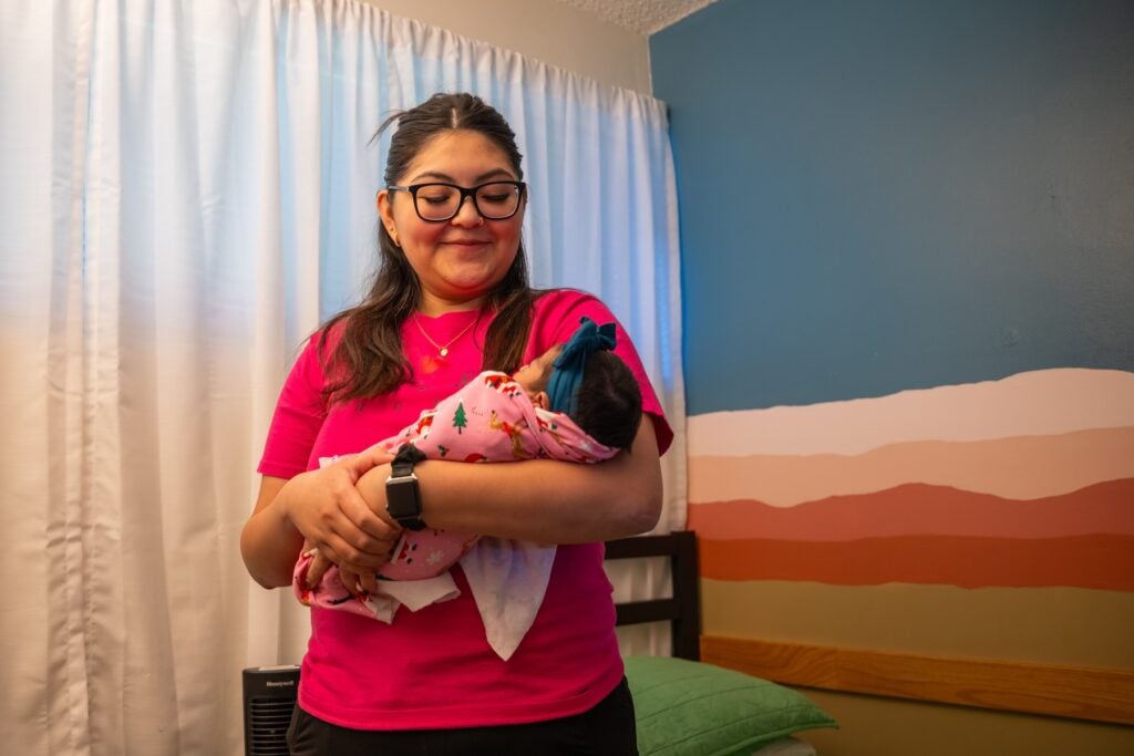 A woman holding an infant wrapped in a blanket