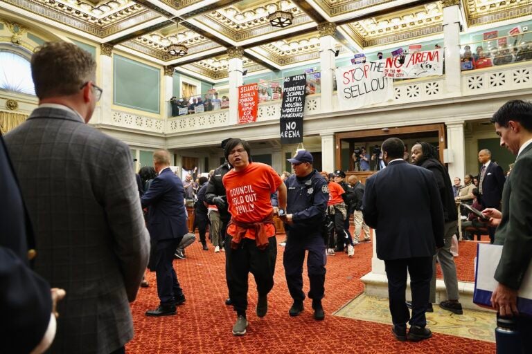 Protester escorted out of council chambers by a police officer.