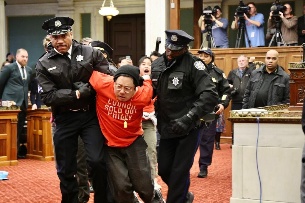 Protester escorted out of council chambers by a police officer.