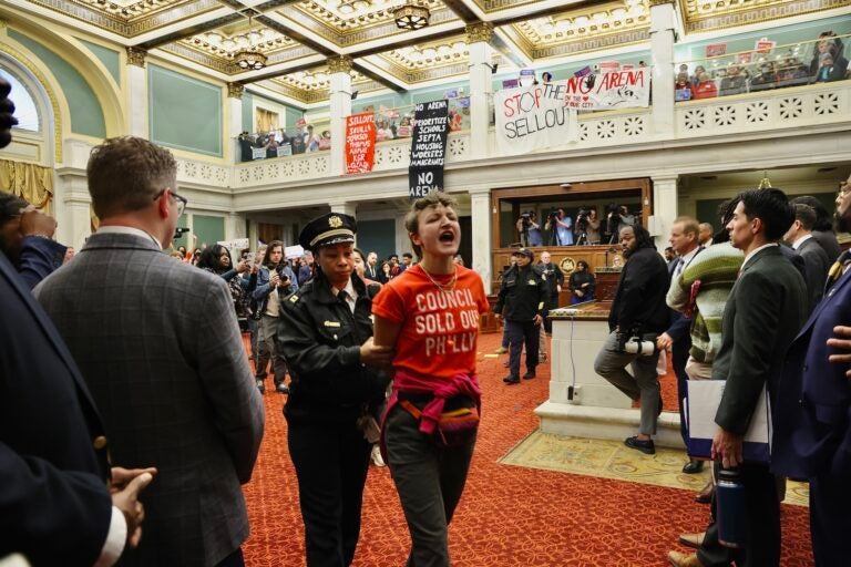 Protester escorted out of council chambers by a police officer.