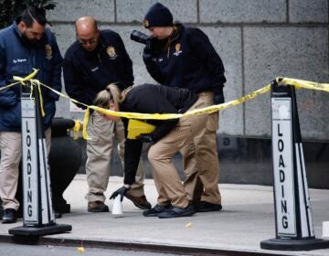 Members of the New York police crime scene unit pick up cups marking the spots where bullets lie as they investigate the scene outside the Hilton Hotel in midtown Manhattan where Brian Thompson, the CEO of UnitedHealthcare, was fatally shot Wednesday, Dec. 4, 2024, in New York.