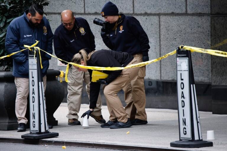 Members of the New York police crime scene unit pick up cups marking the spots where bullets lie as they investigate the scene outside the Hilton Hotel in midtown Manhattan where Brian Thompson, the CEO of UnitedHealthcare, was fatally shot Wednesday, Dec. 4, 2024, in New York.