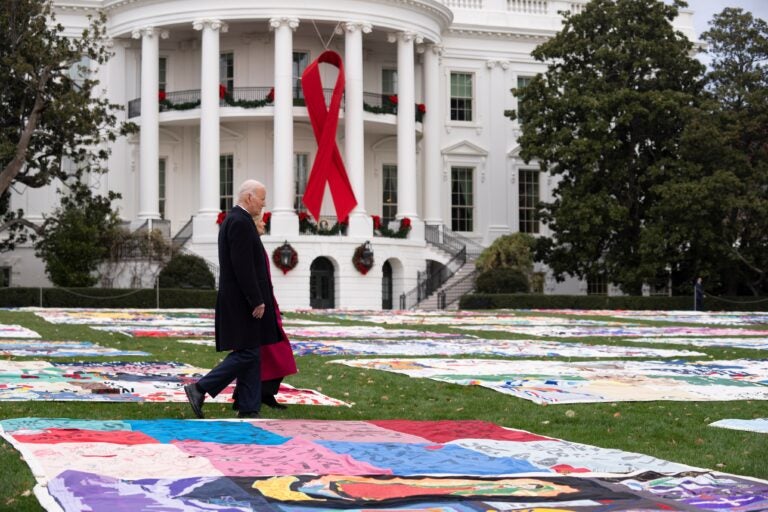 Joe and Jill Biden walk between AIDS Memorial Quilts spread over the South Lawn at the White House